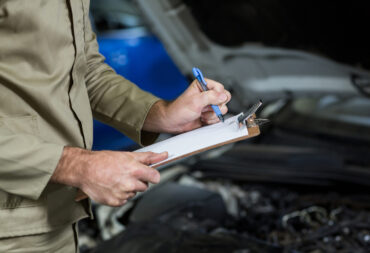 Mid-section of mechanic preparing a check list in repair garage
