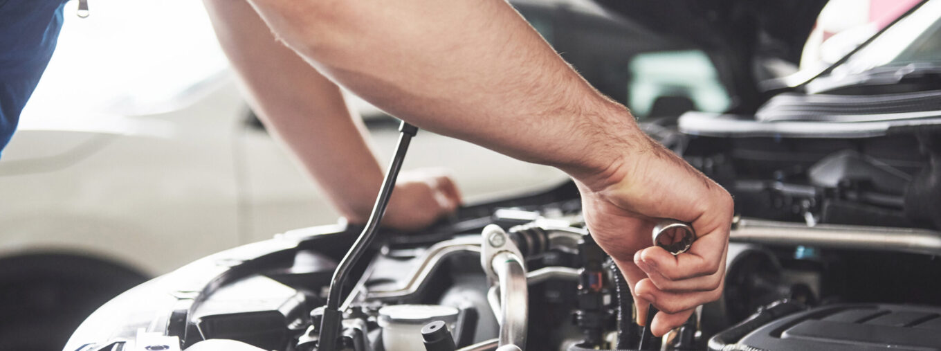 Close up hands of unrecognizable mechanic doing car service and maintenance.